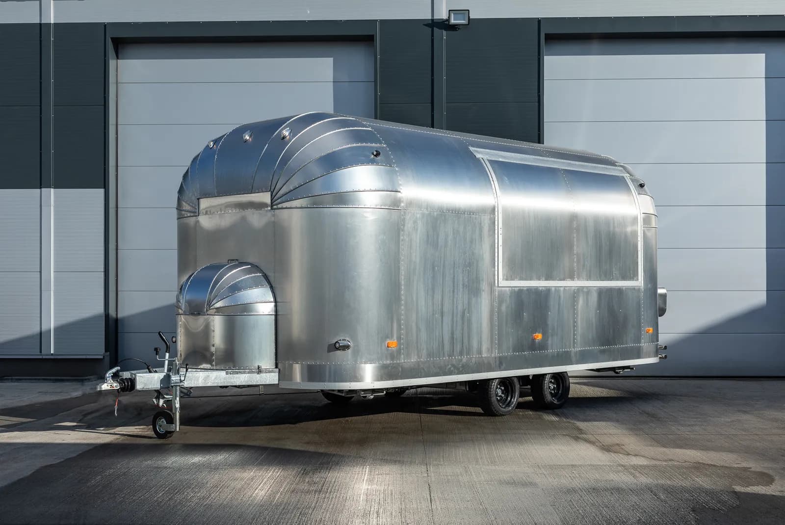 Remorque Mirage de 5,2 m en aluminium poli, à la silhouette Airstream, devant l'atelier du constructeur