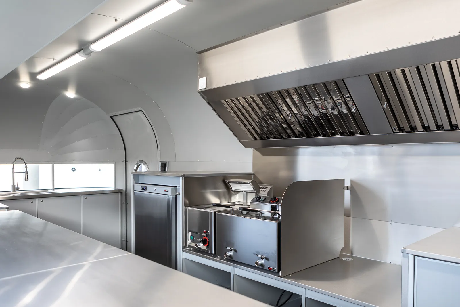 Intérieur d'une remorque Mirage équipée en cuisine professionnelle inox, hotte et plans de travail