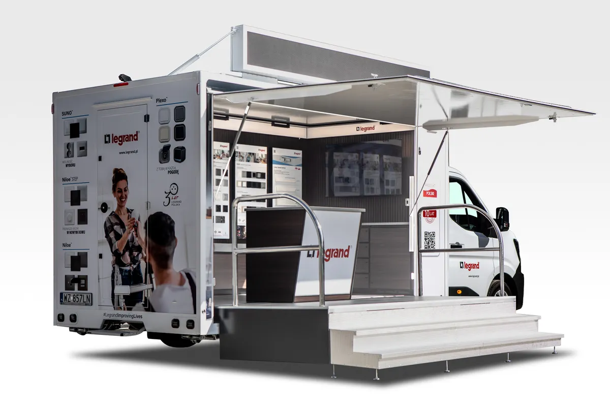 Camion événementiel aux couleurs de Legrand, trappe ouverte sur un showroom de prises et interrupteurs