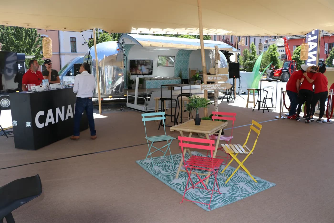 Stand Canal+ avec caravane Airstream, tapis et mobilier de terrasse colorés