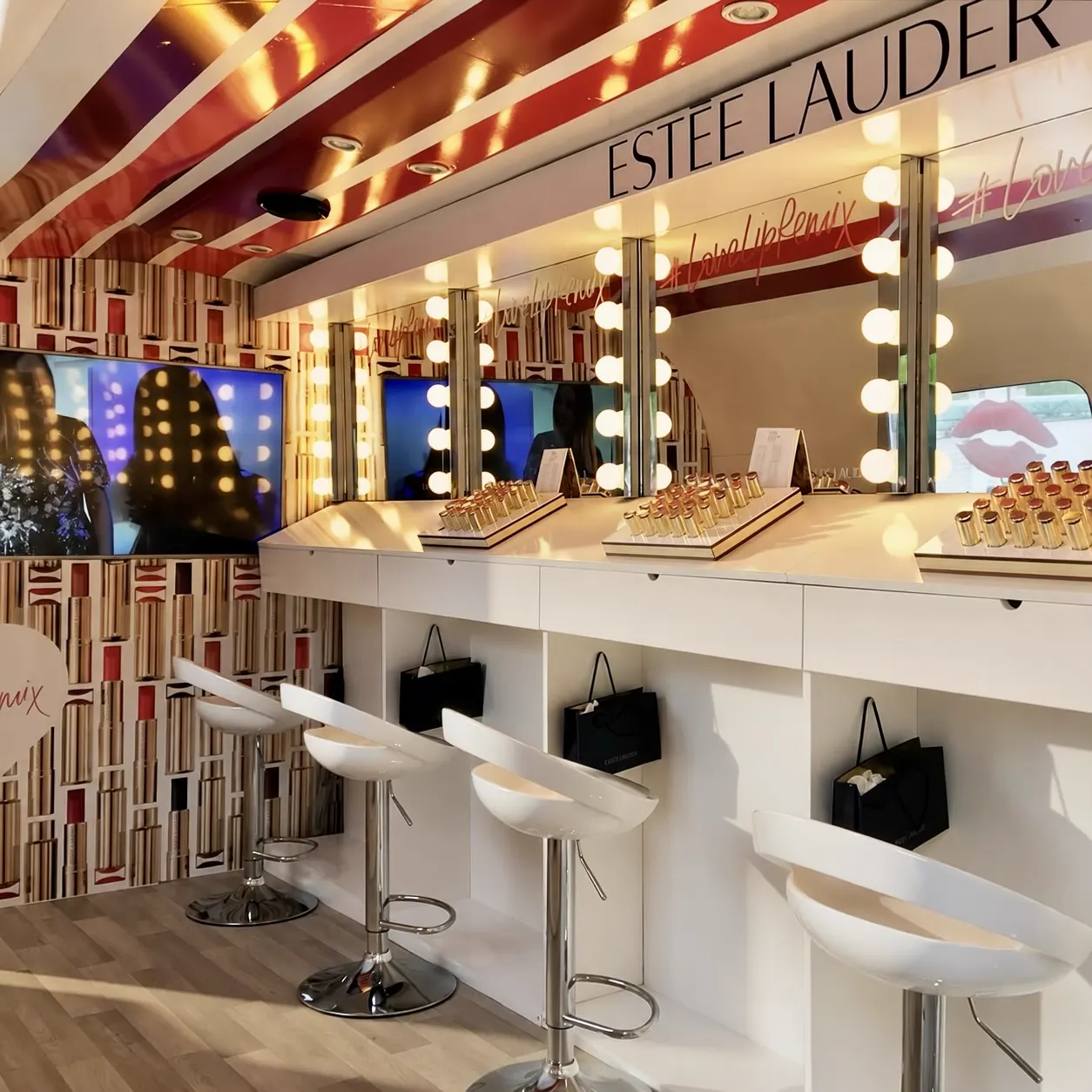Intérieur aménagé en espace de maquillage : coiffeuses, miroirs à ampoules et tabourets