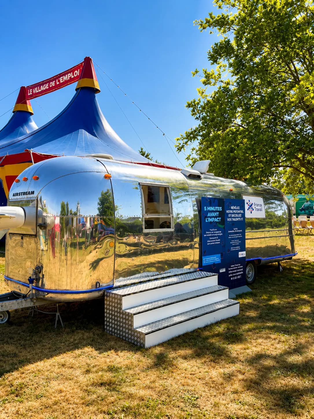 Airstream Sovereign habillée et chapiteau bleu et jaune sur une pelouse