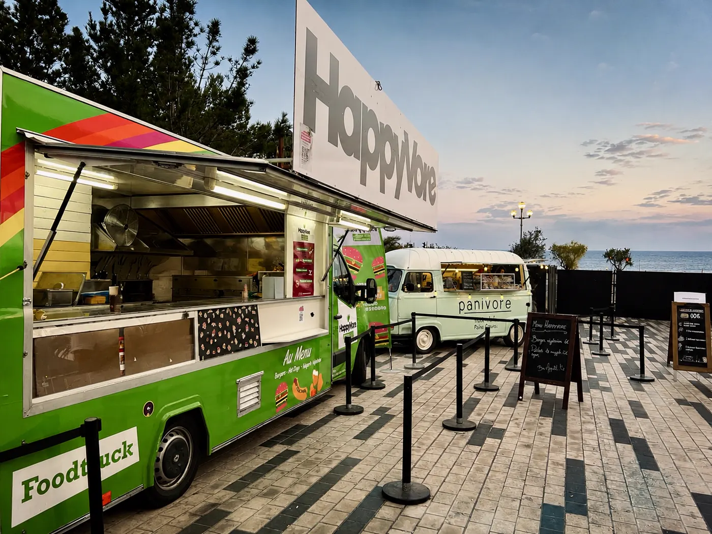 Foodtruck vert ouvert sur son comptoir, file d'attente balisée devant le véhicule
