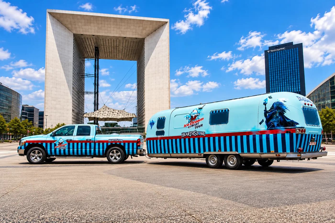 Pick-up et caravane Airstream habillés en bleu devant la Grande Arche de la Défense