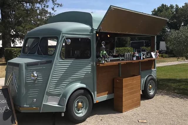 Citroën HY aménagé en bar, comptoir ouvert et auvent relevé dans un jardin