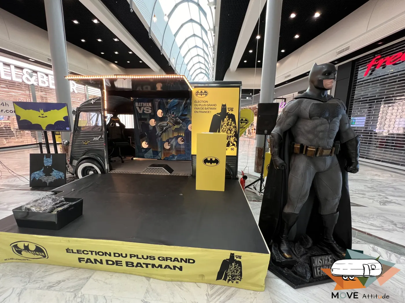 Scène d'animation habillée aux couleurs d'un super-héros, statue grandeur nature et banderole « Élection du plus grand fan de Batman »