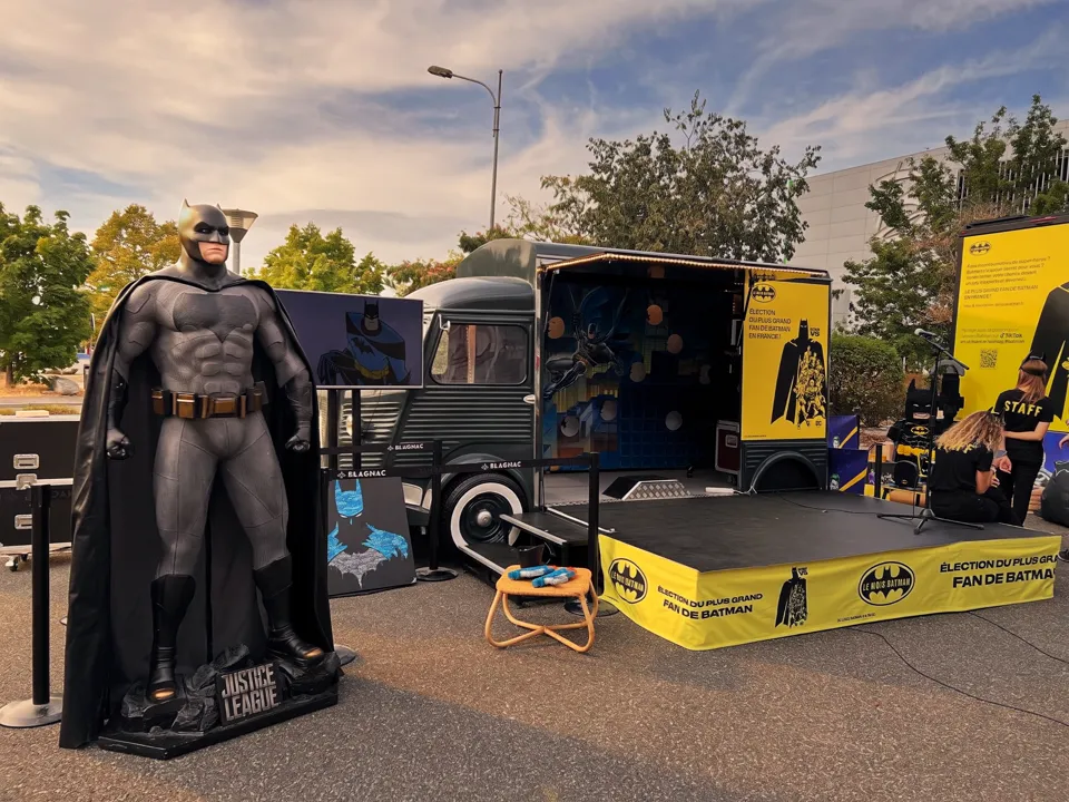 Statue de Batman grandeur nature devant une remorque Citroën HY aménagée en stand, dans une galerie commerciale